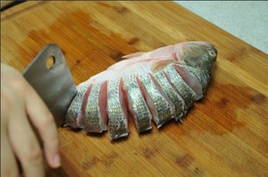 將鱸魚(yú)清洗干凈，從脊椎處切斷至腹部，腹部保留1cm左右不要切斷。